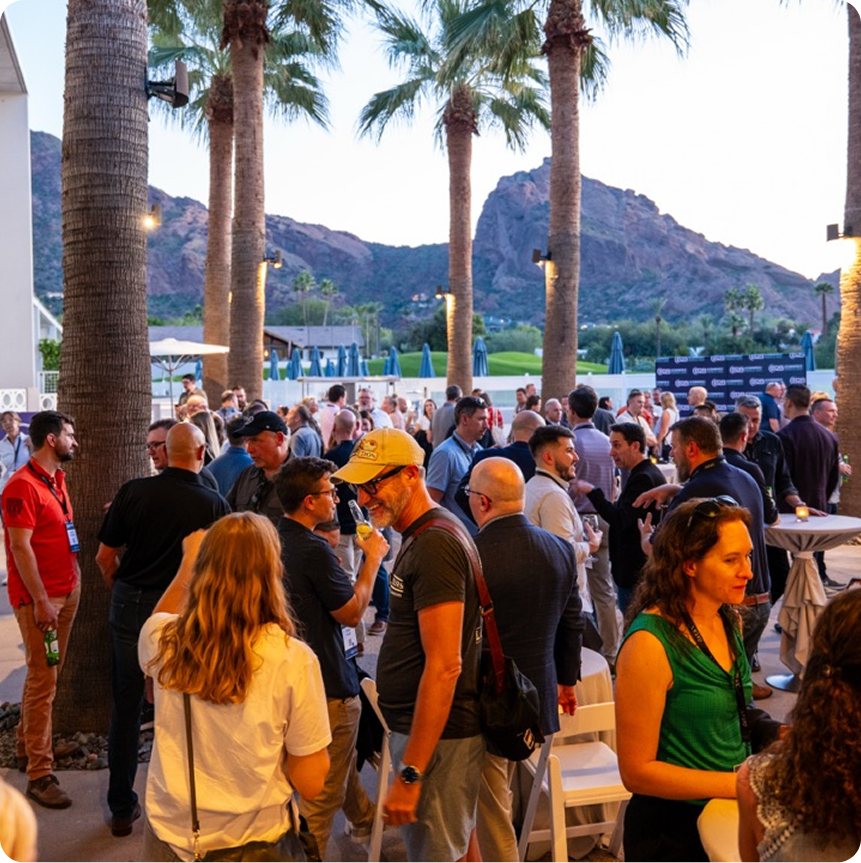 Attendees networking at B2B NEXT AI summit with palm trees and Camelback Mountain in the background